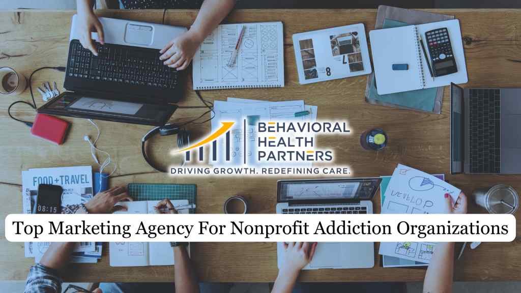 Group working at a table with laptops, notebooks, and a drink. "Behavioral Health Partners" logo at center. Text: "Top Marketing Agency for Nonprofit Addiction Organizations."